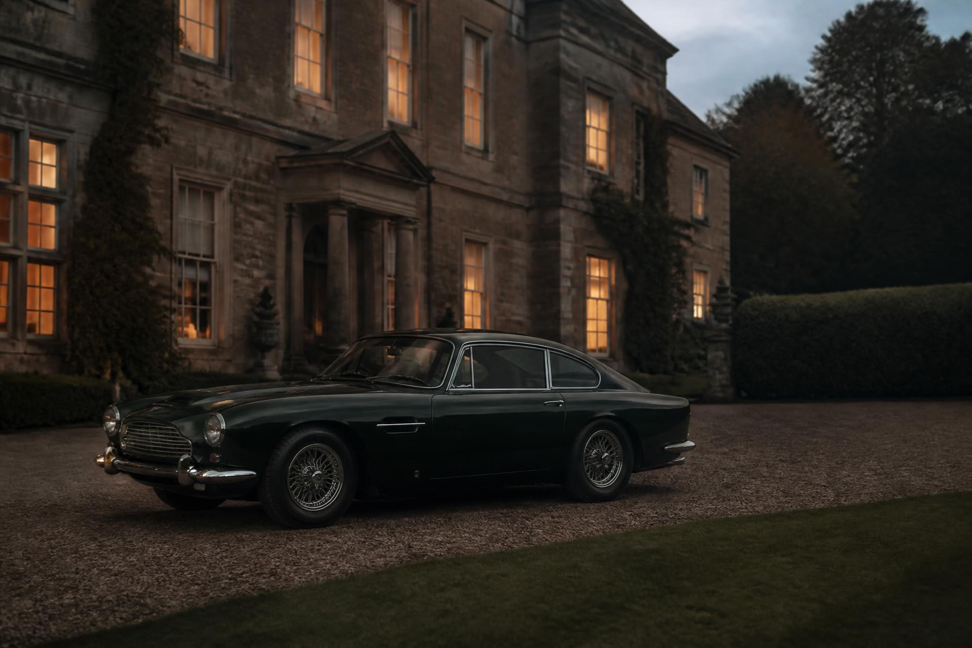 Dark green vintage grand tourer parked on gravel outside a lit country house at dusk